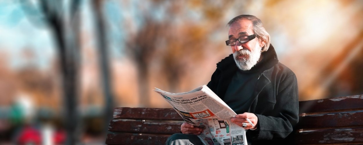 Elderly Man Reading Newspaper on Bench