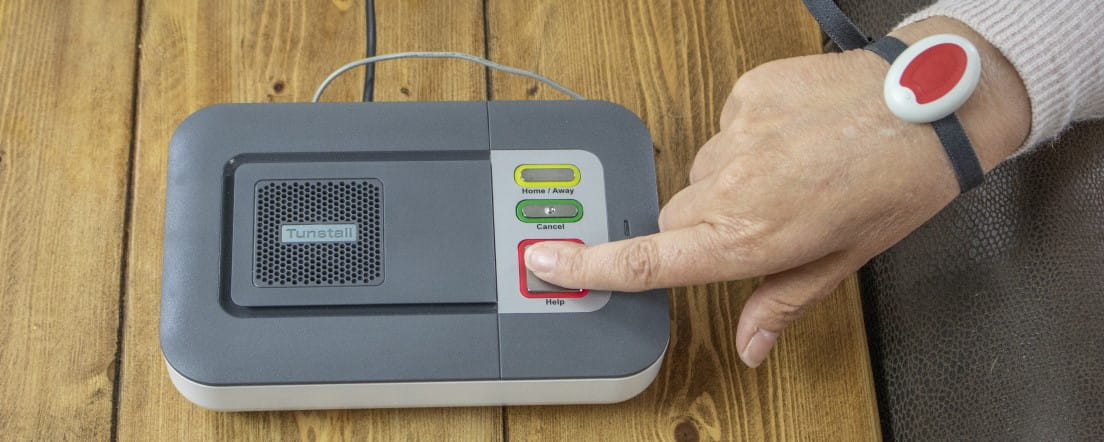 Careline alarm user pressing the red button on the base unit