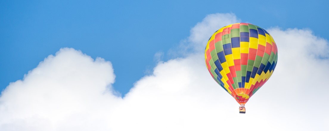 Hot air balloon in cloudy blue sky