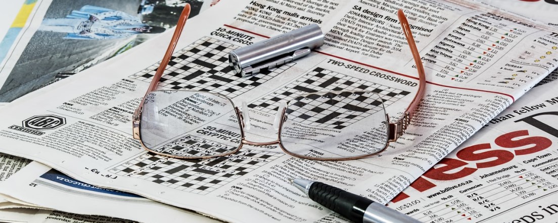 crossword in newspaper with glasses and pen