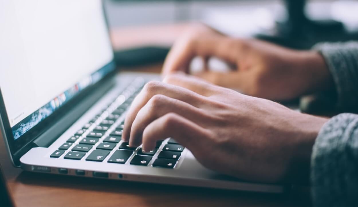 elderly person typing on a laptop