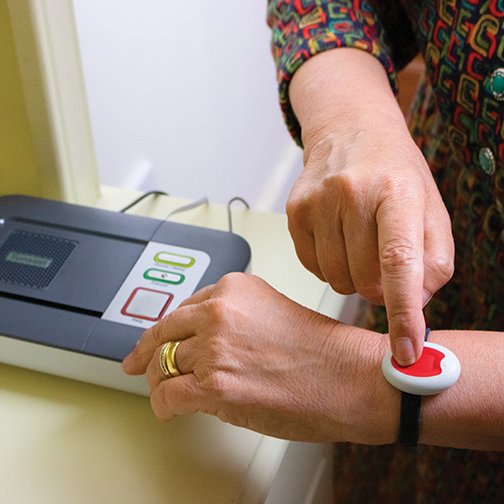 Elderly lady pressing her Careline alarm pendant