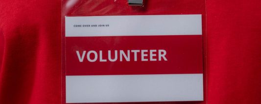 person wearing an id card telling people to try volunteering